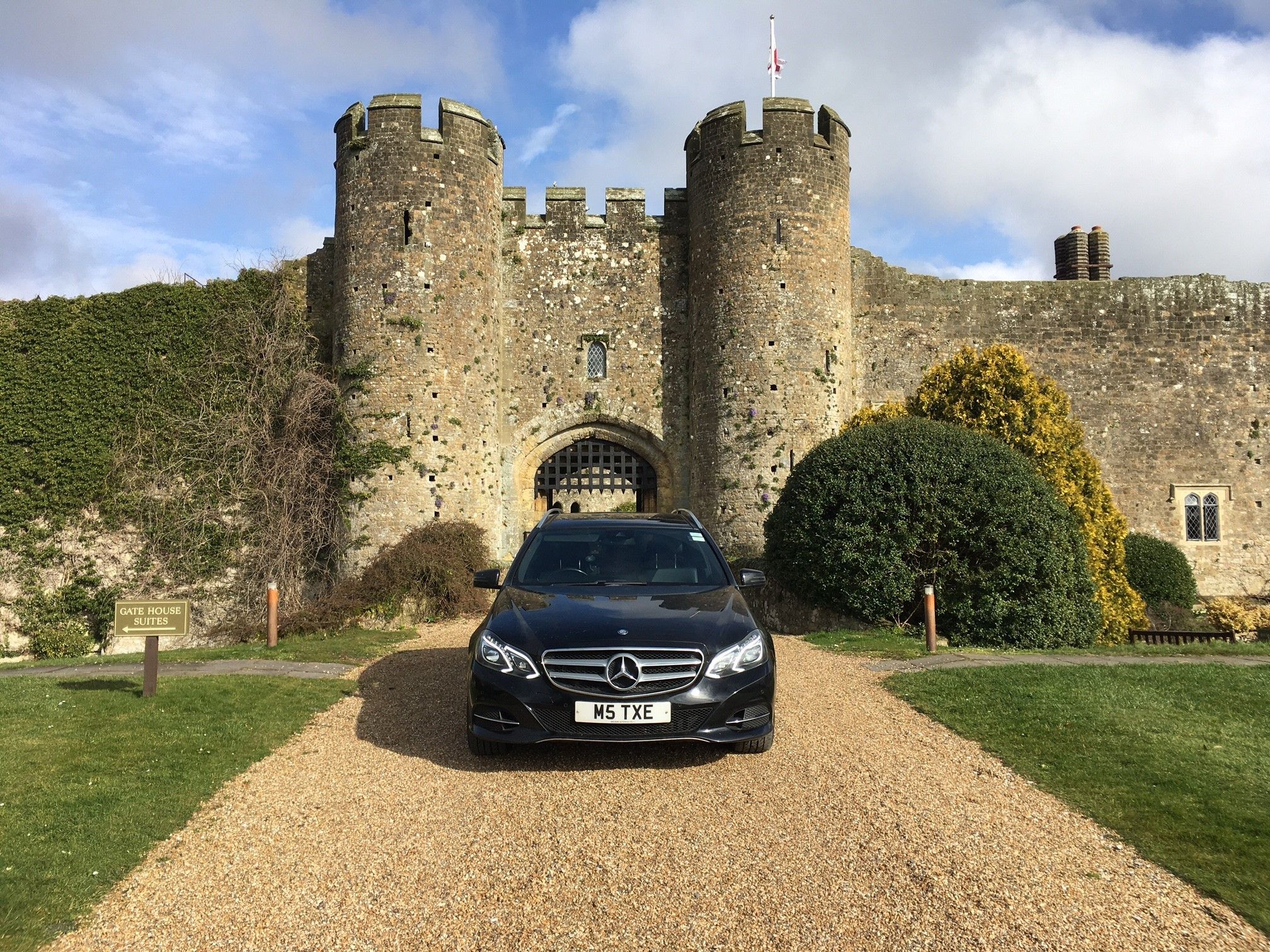 Black Mercedes-Benz E-Class estate in front of a castle gatehouse